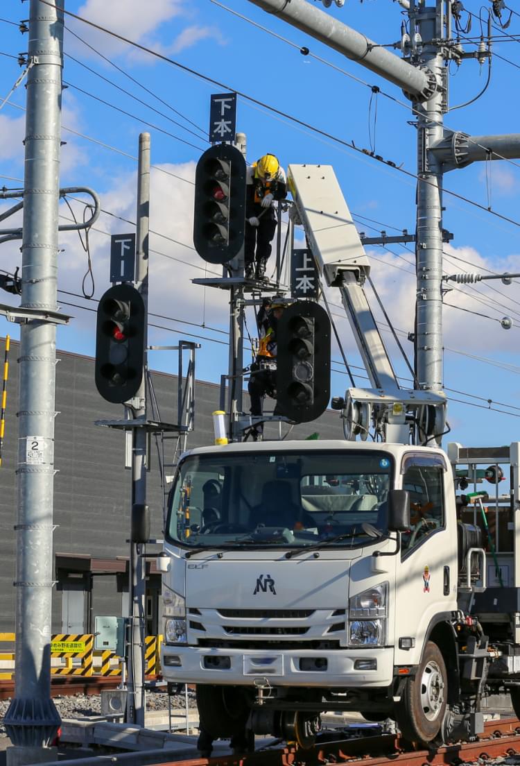 鉄道工事専用車両を活用した信号機の据付をする写真