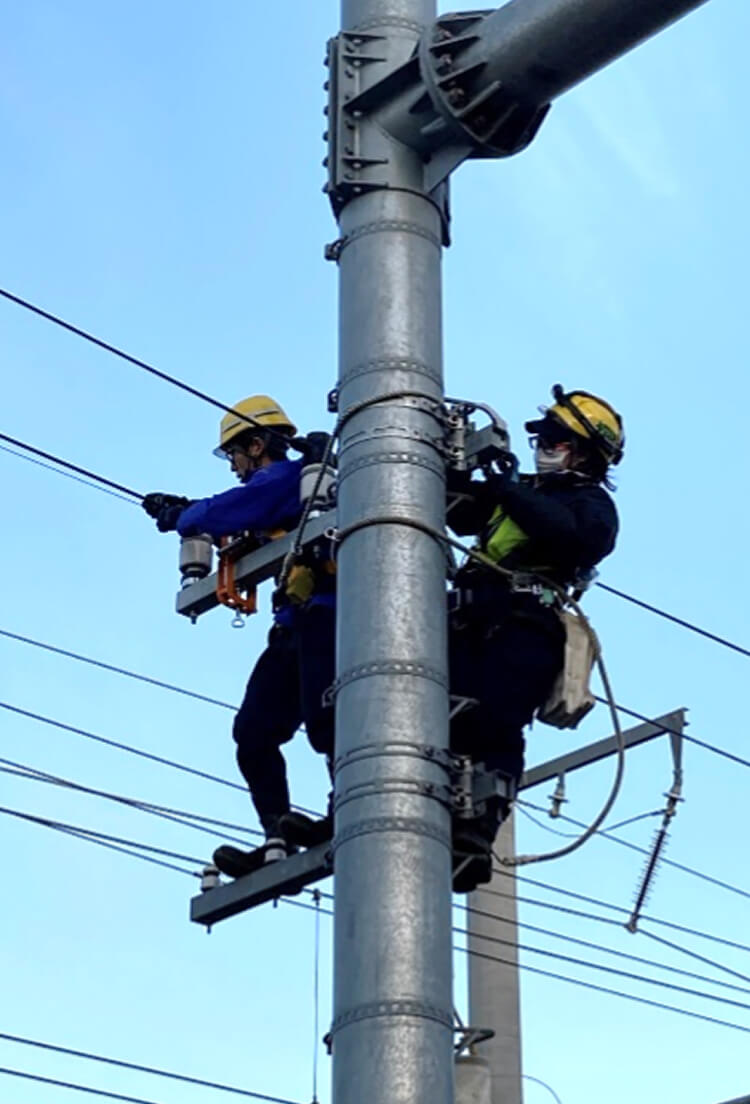 電柱に登り配電線の修繕工事をする写真